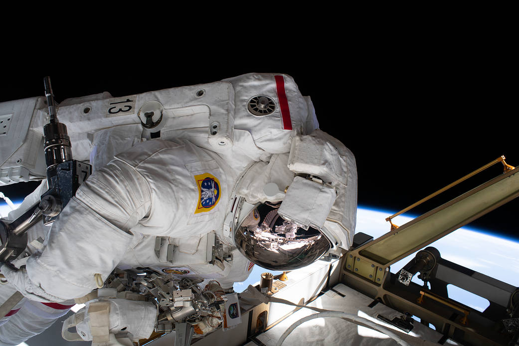 The reflection in Jessica Meir's spacesuit helmet is Christina Koch