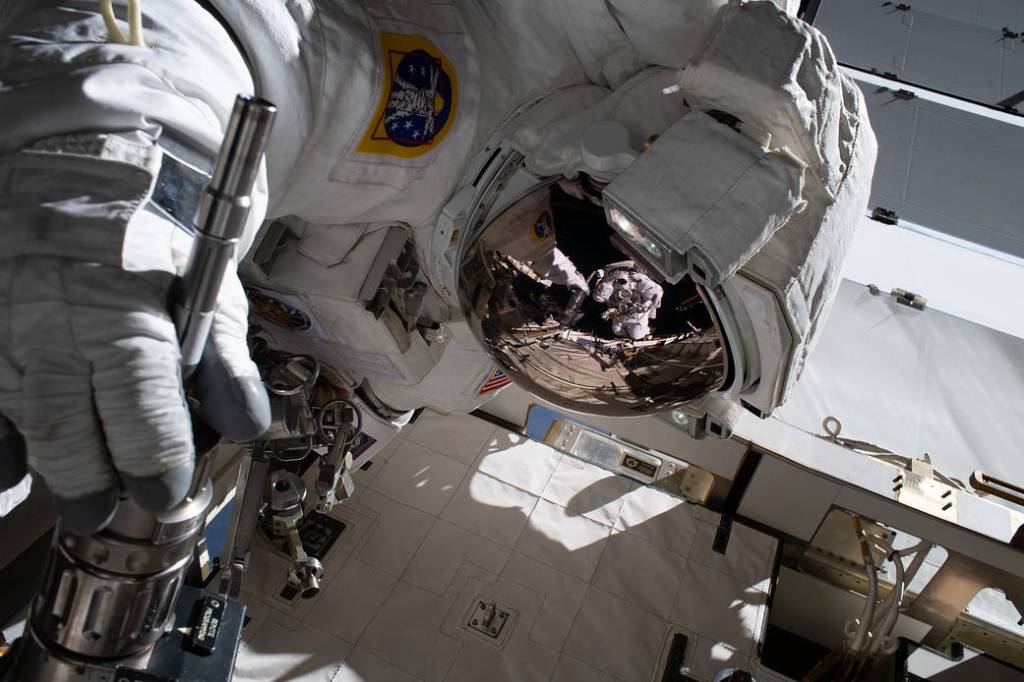 The reflection in Jessica Meir’s spacesuit helmet is Christina Koch