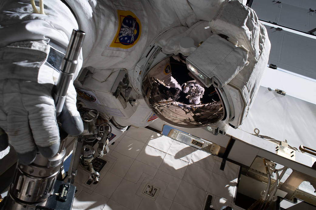 The reflection in Jessica Meir's spacesuit helmet is Christina Koch