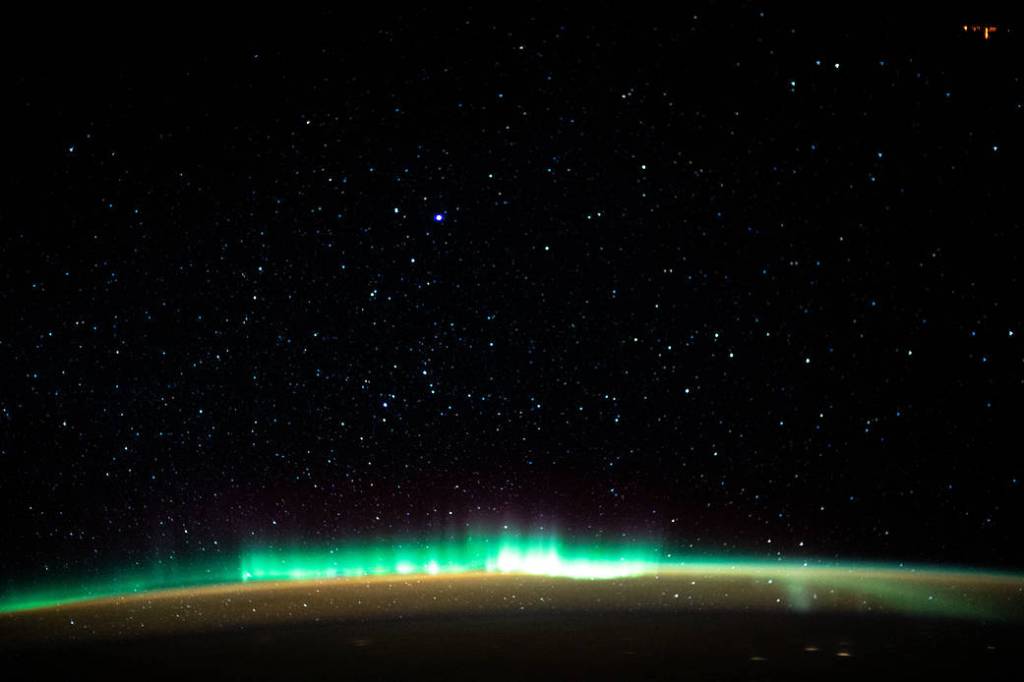 An aurora blankets the Earth beneath a celestial night sky