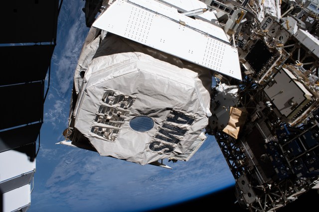 The Alpha Magnetic Spectrometer, an antimatter and dark matter detector, is wrapped in shielding labeled with the research device's acronym, AMS. View taken during ISS EVA 64.