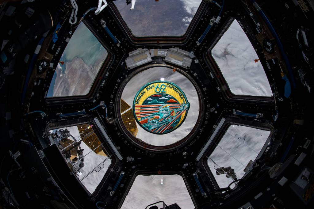 The Expedition 62 mission patch floats inside the seven-window cupola