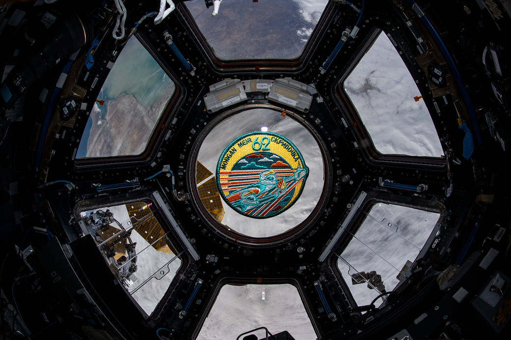 The Expedition 62 mission patch floats inside the seven-window cupola