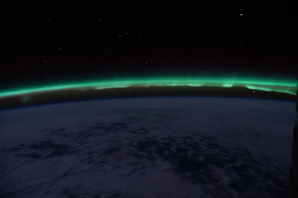 The “aurora australis” hovers above the Earth’s horizon