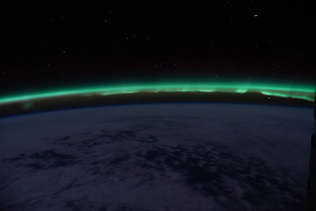 The "aurora australis" hovers above the Earth's horizon
