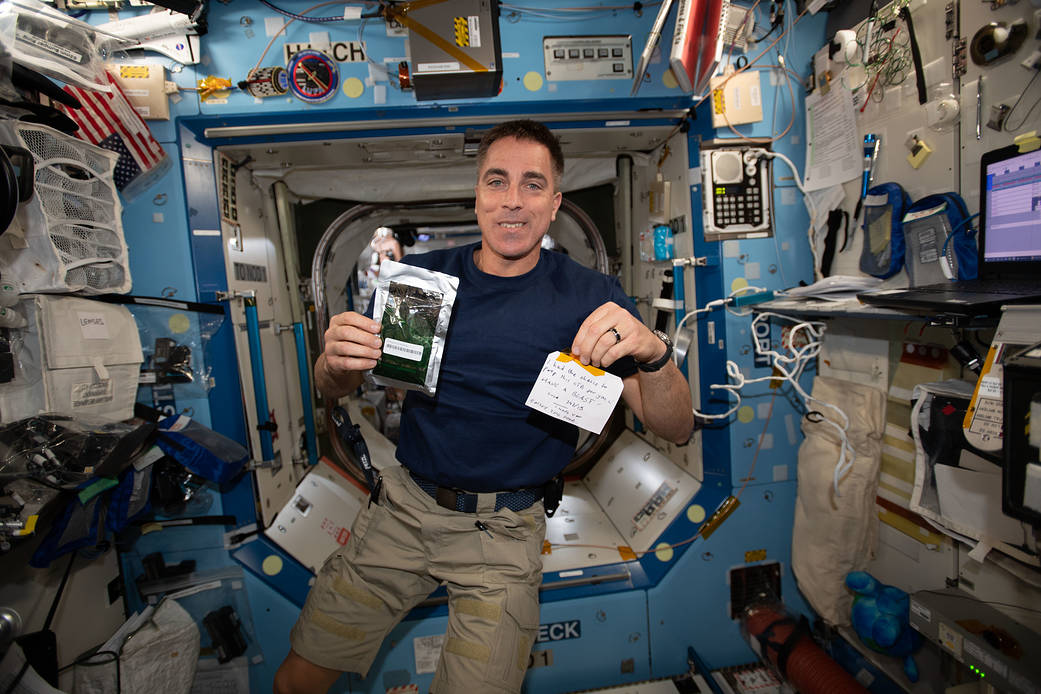 Astronaut Chris Cassidy holds a Parmigiana di Melanzane meal packet