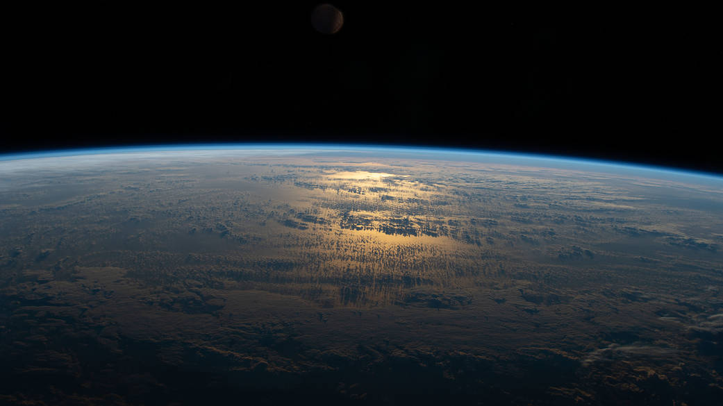 The sun's glint beams off a partly cloudy South Pacific