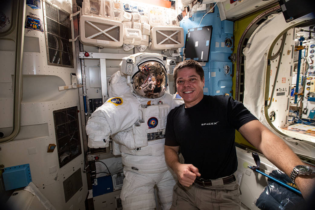 NASA astronaut Bob Behnken poses with a U.S. spacesuit