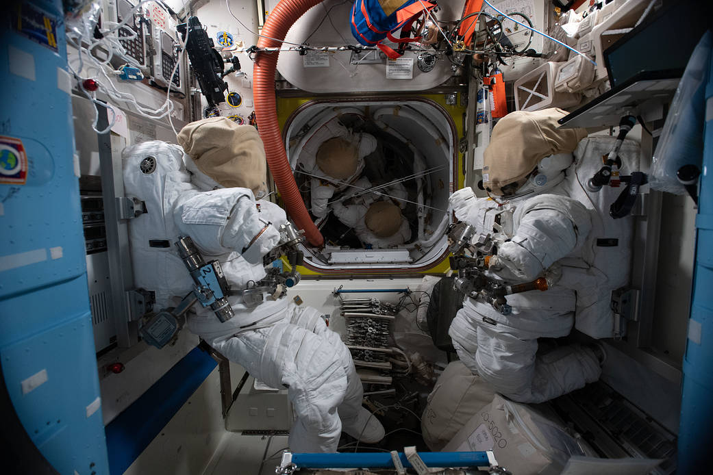 Four U.S. spacesuits are pictured inside the Quest airlock