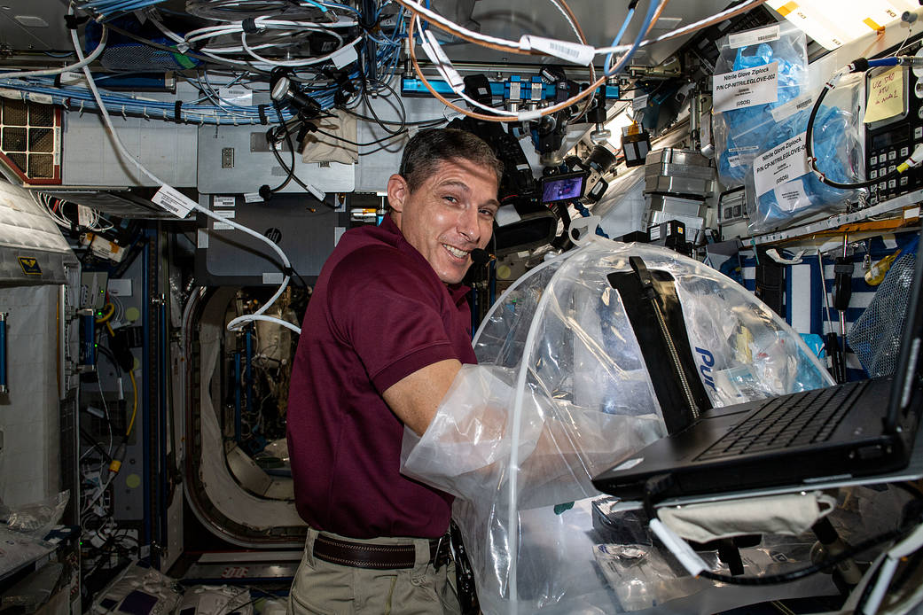 Astronaut Michael Hopkins works science inside a portable glovebag