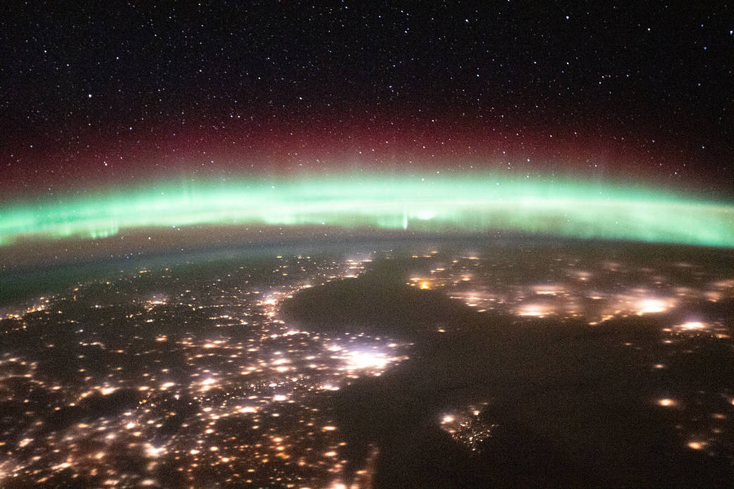An aurora above the city lights of Sweden and Finland