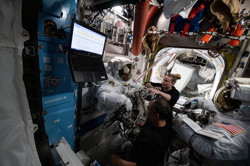 Astronaut Kate Rubins assists crewmates during spacesuit fit check