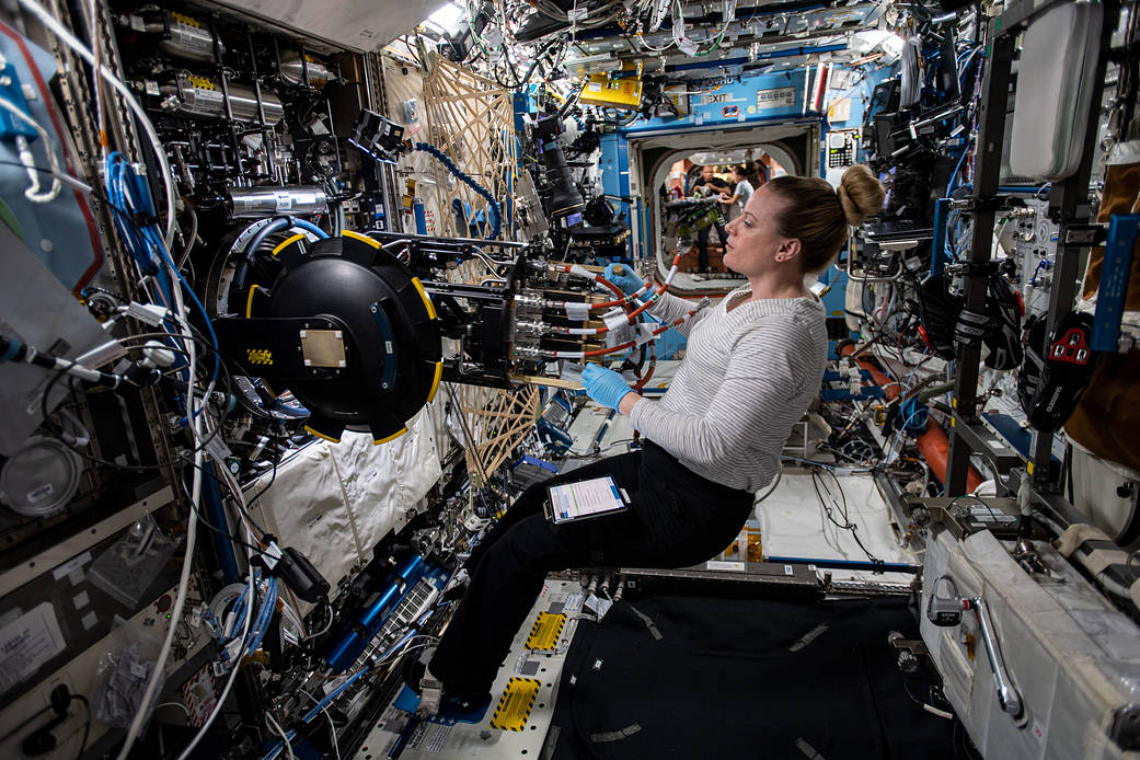 NASA astronaut Kate Rubins removes combustion research hardware