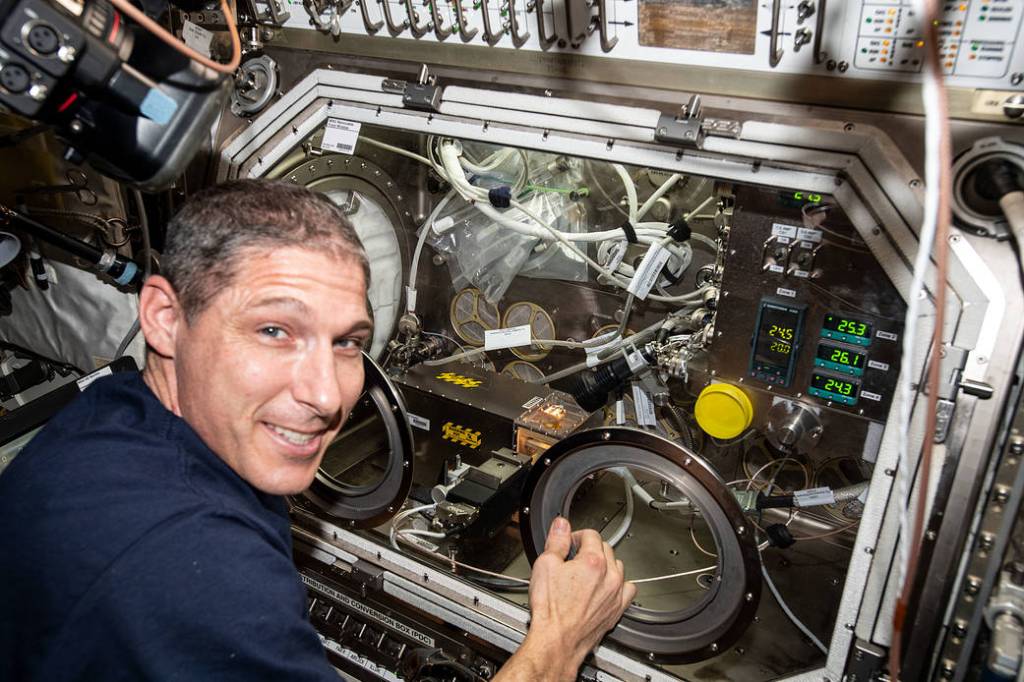 Astronaut Michael Hopkins swaps samples inside the Microgravity Science Glovebox