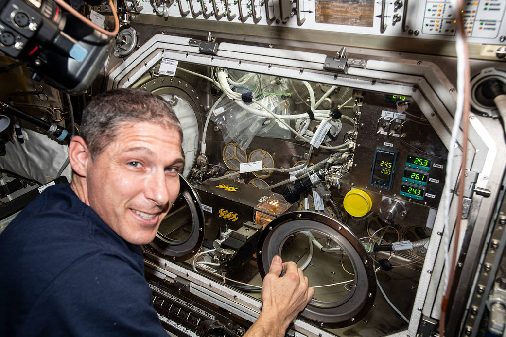 Astronaut Michael Hopkins swaps samples inside the Microgravity Science Glovebox