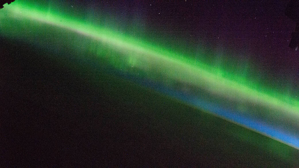 An aurora glows above the Earth's horizon