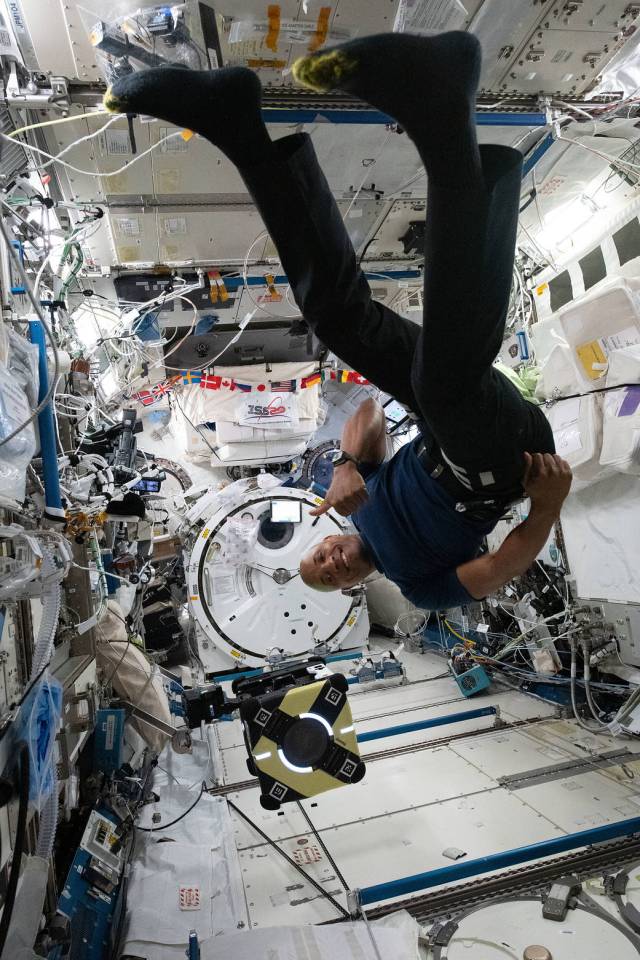 NASA astronaut Victor Glover works with an Astrobee robot.