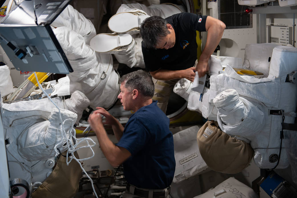 Astronauts Shane Kimbrough and Akihiko Hoshide work on spacesuits