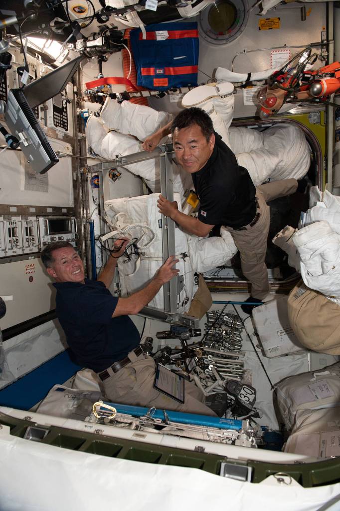 Astronauts Shane Kimbrough and Akihiko Hoshide work on spacesuits