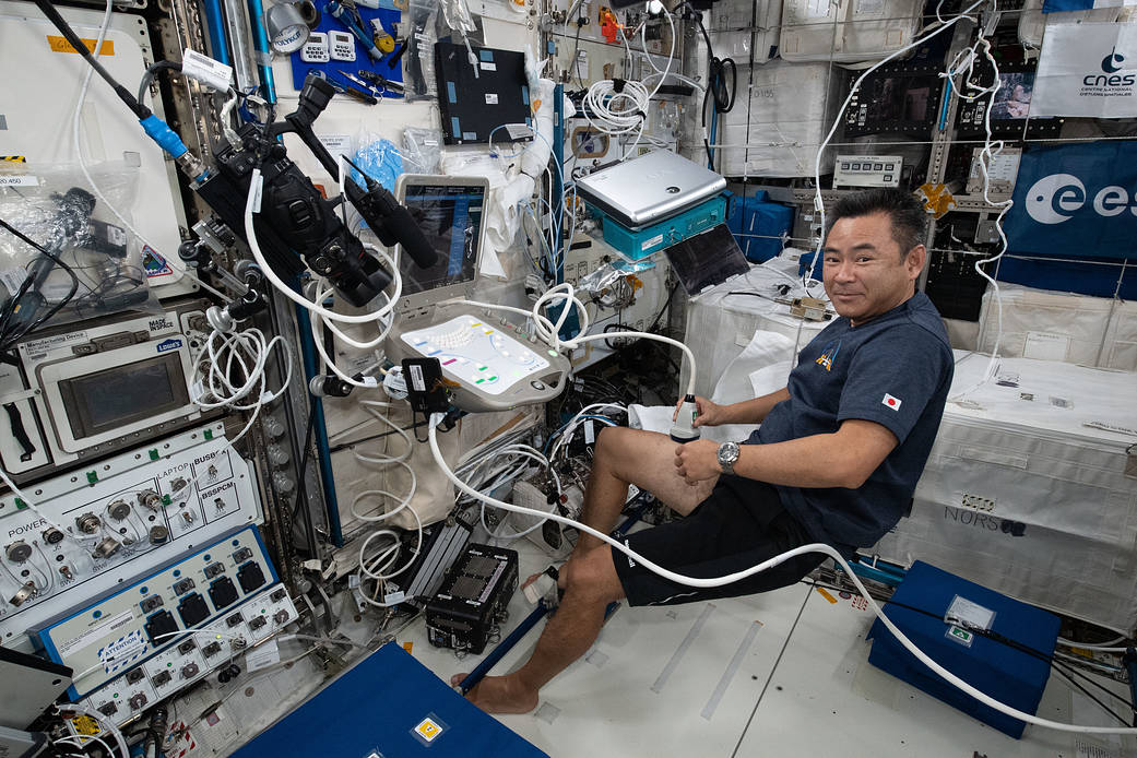 Astronaut Akihiko Hoshide scans his leg with an ultrasound device