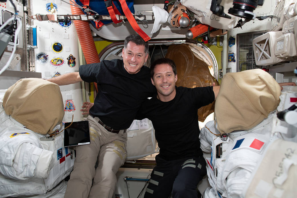 Astronauts Shane Kimbrough and Thomas Pesquet work on spacesuits