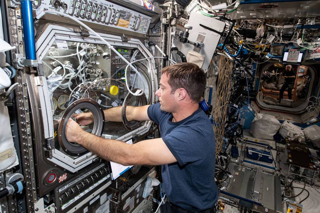 Astronaut Thomas Pesquet swaps samples inside the Microgravity Sciences Glovebox