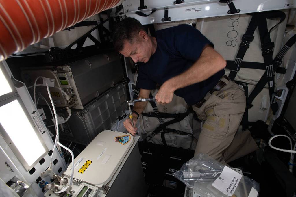 Astronaut Shane Kimbrough loads a science freezer inside Cargo Dragon