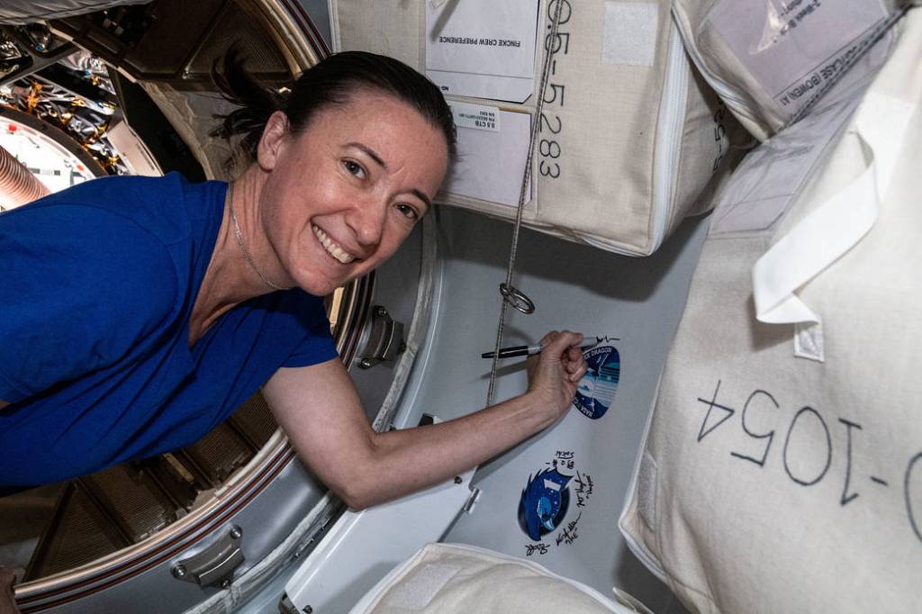 Astronaut Megan McArthur signs her name next to a mission sticker