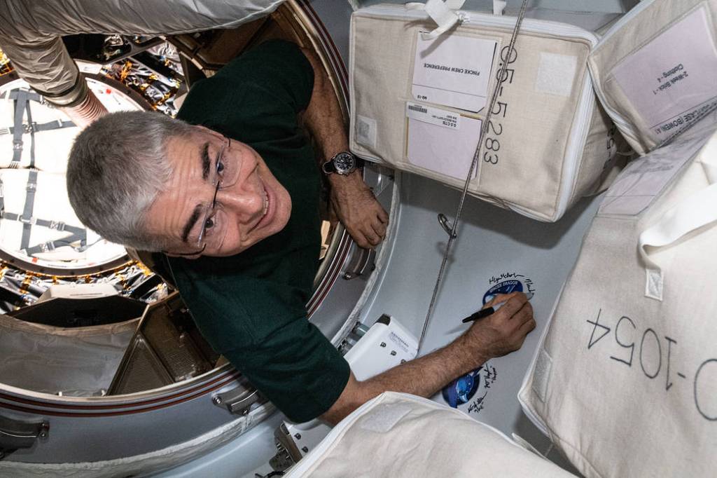 Astronaut Mark Vande Hei signs his name next to a mission sticker