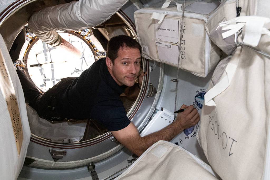 Astronaut Thomas Pesquet signs his name next to a mission sticker