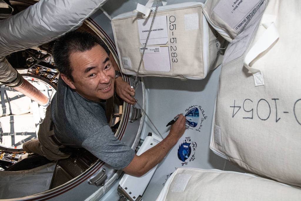 Astronaut Akihiko Hoshide signs his name next to a mission sticker