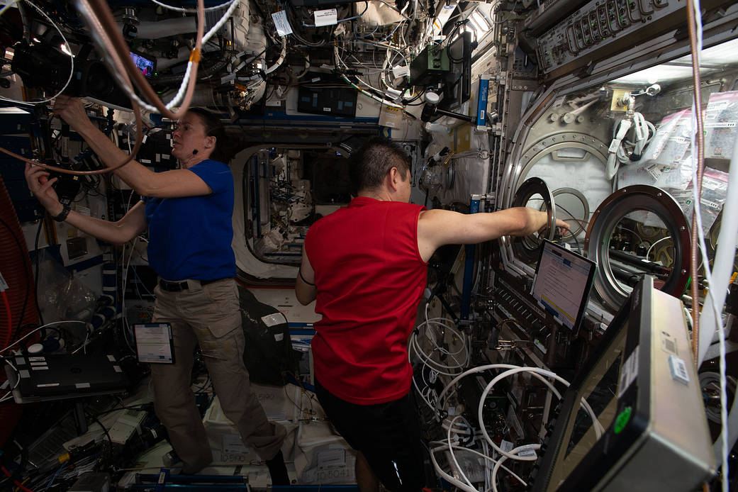 Astronauts Megan McArthur and Akihiko Hoshide work on science maintenance