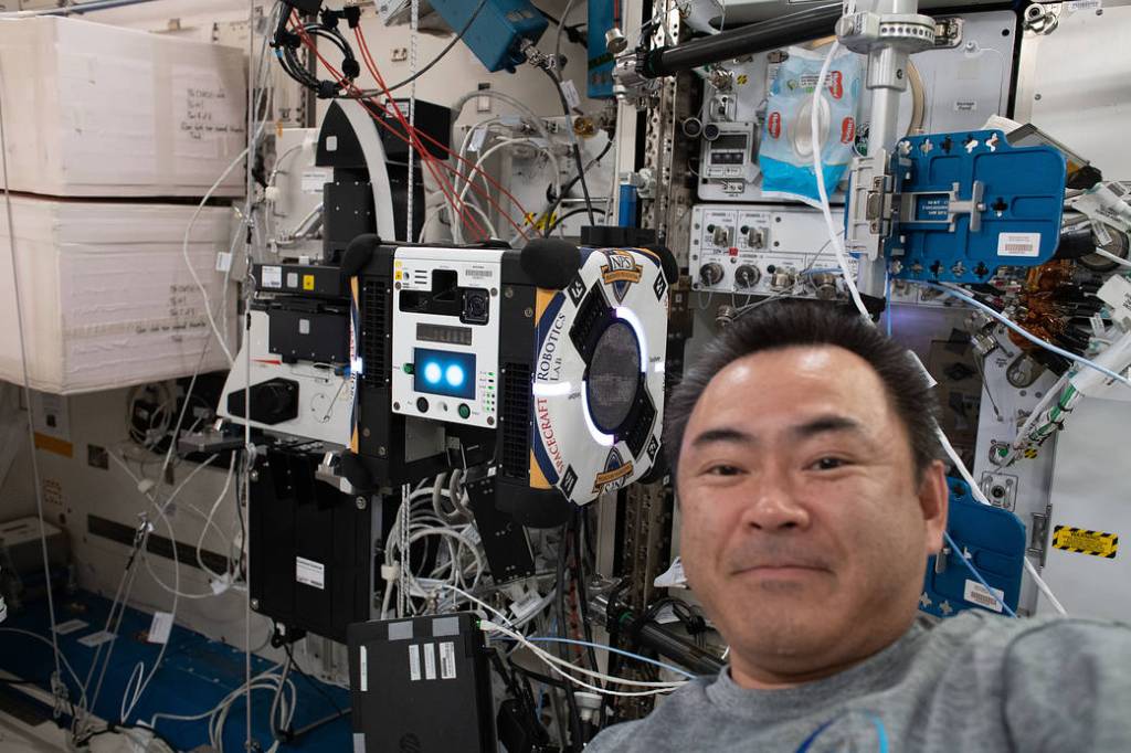 Astronaut Akihiko Hoshide poses with an Astrobee robotic assistant