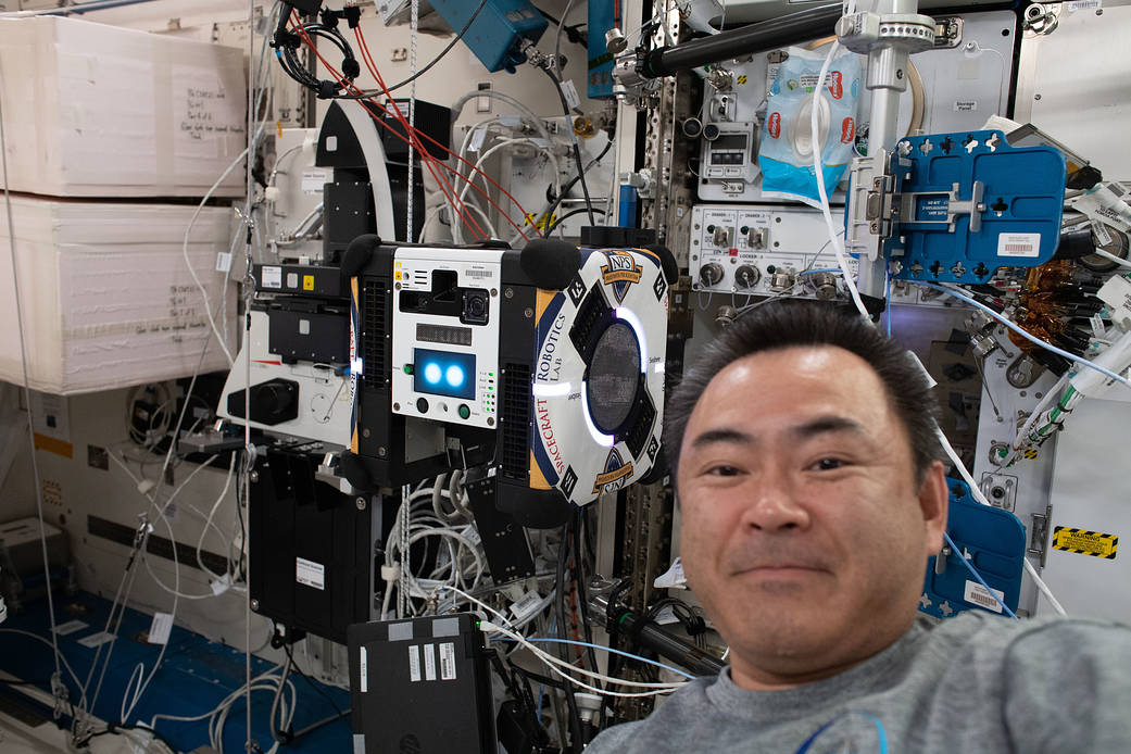 Astronaut Akihiko Hoshide poses with an Astrobee robotic assistant