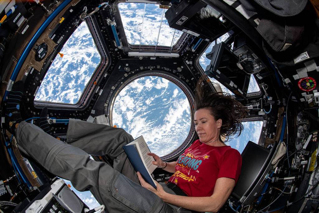 NASA astronaut Megan McArthur reads a book in the cupola