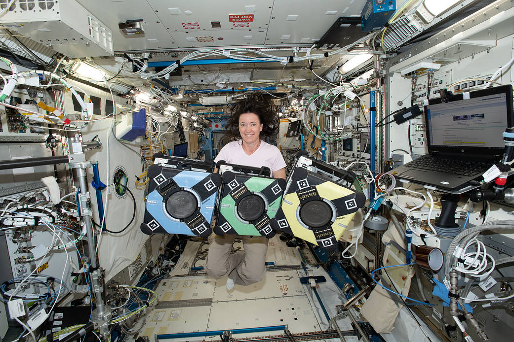 NASA astronaut Megan McArthur poses with the Astrobee robotic free-flyers aboard the International Space Station.