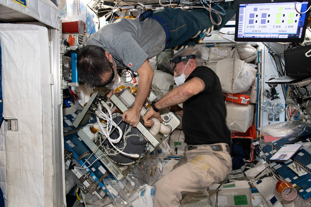 Astronauts Akihiko Hoshide and Mark Vande Hei work on orbital plumbing tasks.