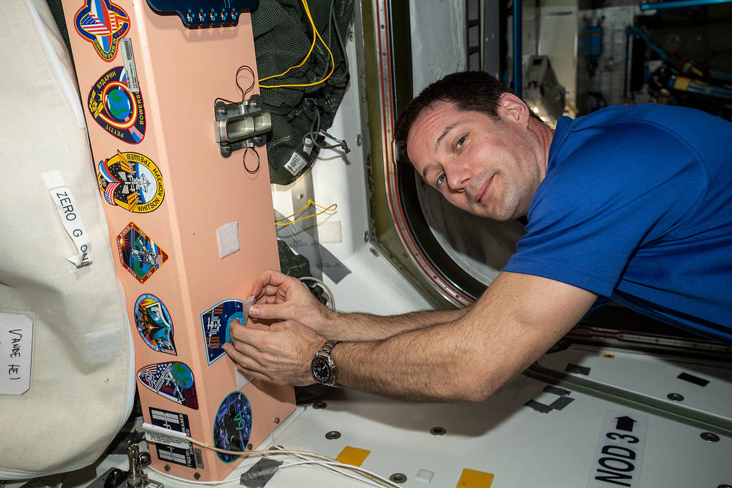 Astronaut Thomas Pesquet affixes his mission's insignia sticker