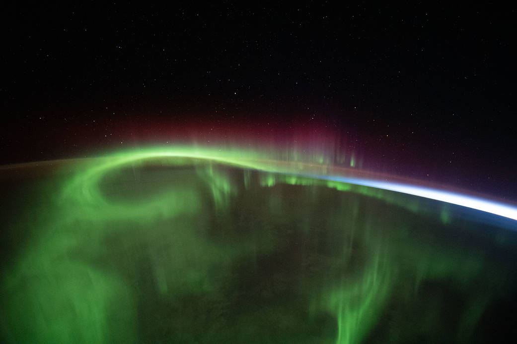 A aurora vividly streams over the Earth