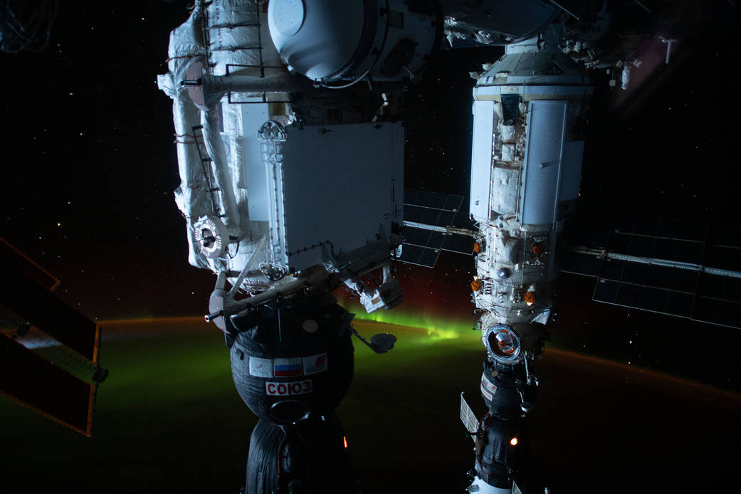 An aurora is pictured below the International Space Station as it was orbiting 274 miles above the southern Pacific Ocean just south of Auckland Island, New Zealand. In the foreground (from left) are, the Soyuz MS-19 crew ship docked to the Rassvet module and the Soyuz MS-18 crew ship docked to the Nauka multipurpose laboratory module.