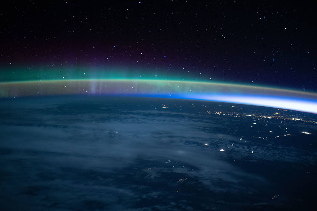 An aurora dimly intersects with Earth's airglow