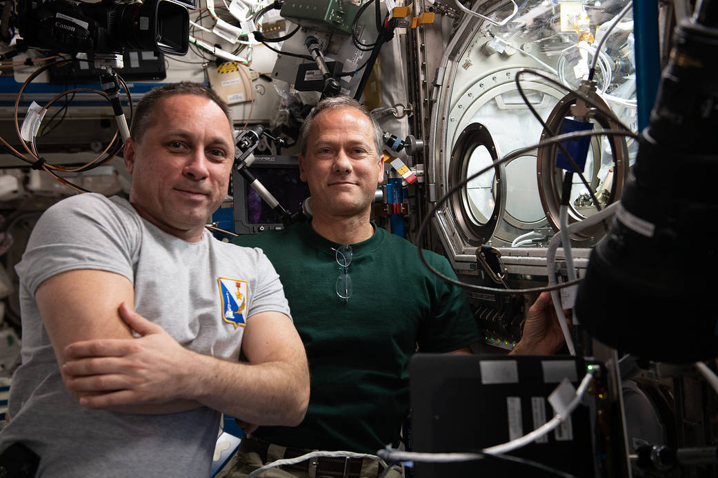 Expedition 66 crew members work on a space physics experiment