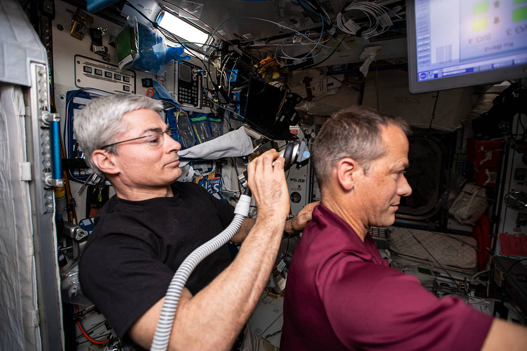 Astronaut Mark Vande Hei gives a haircut to astronaut Thomas Marshburn