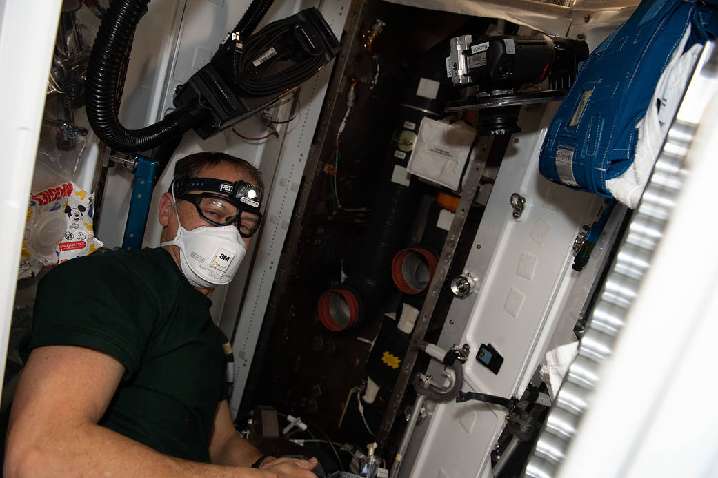 Astronaut Thomas Marshburn cleans the station's ventilation system