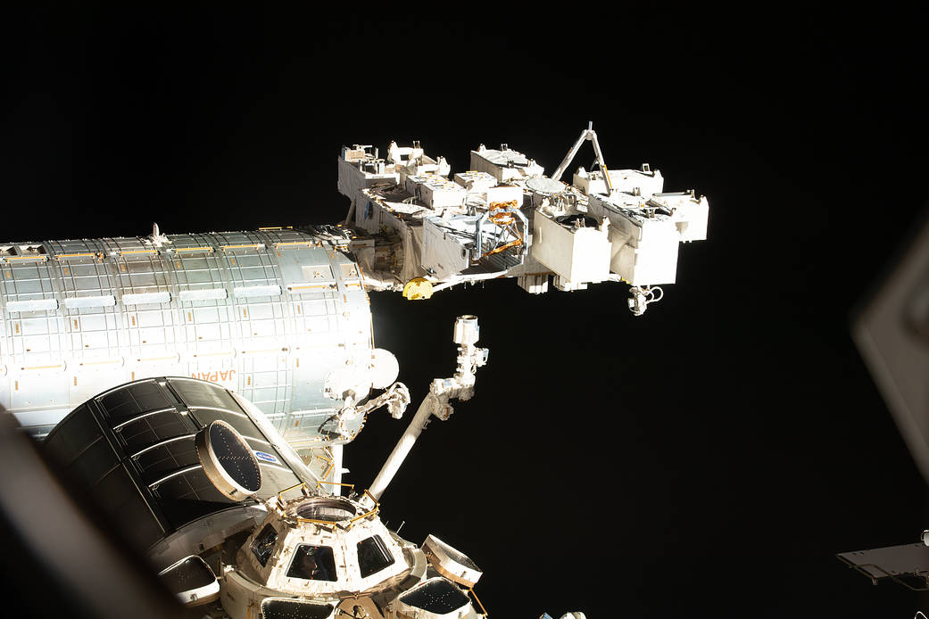 NASA astronaut Flight Engineer Kayla Barron peers out from a window inside the cupola, the International Space Station's "window to the world." Prominent components in this photograph include the Soyuz MS-19 crew ship, the Kibo laboratory module and its external pallet, and the Permanent Multipurpose Module.