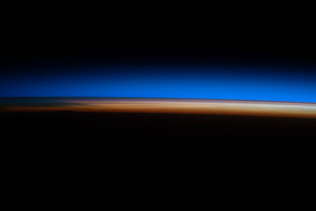 The first rays of an orbital sunrise illuminate Earth's atmosphere