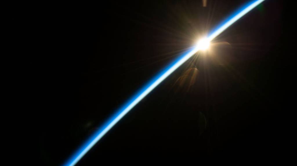 The first rays of an orbital sunrise illuminate the Earth’s atmosphere