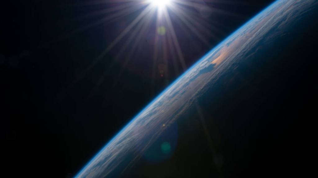 The sun rises above the horizon illuminating the Earth