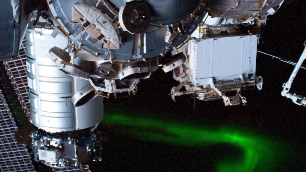 The International Space Station soars above an aurora