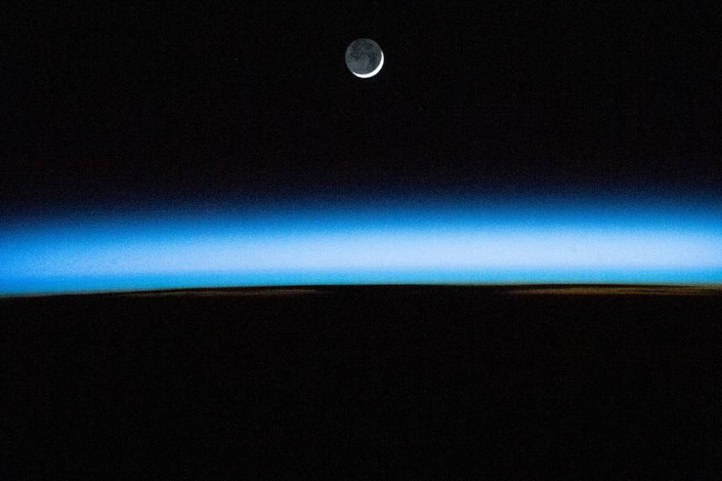 The waxing crescent Moon is pictured above Earth’s atmosphere